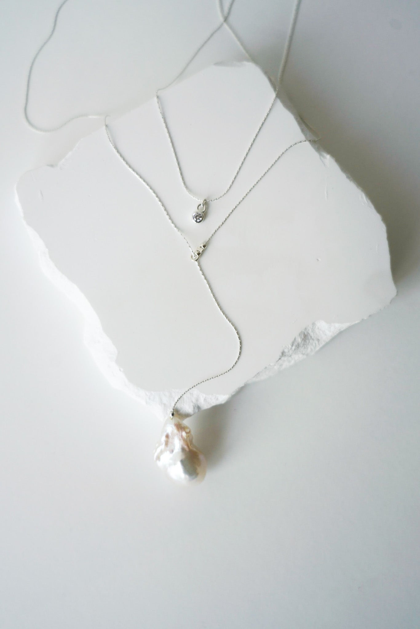 collier de dos pour une mariée avec une chaine argenté et une perle naturelle baroque irrégulière sur l'arrière et un petit cristal sur le devant