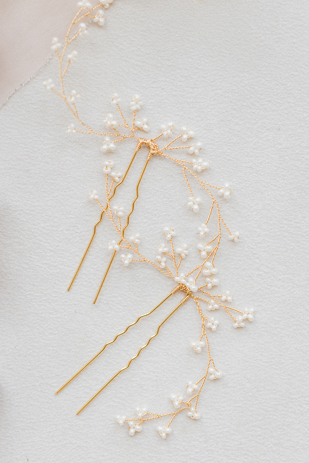 pic à cheveux pour mariage sur un table blanche avec des perles rocailles et du fil dorée