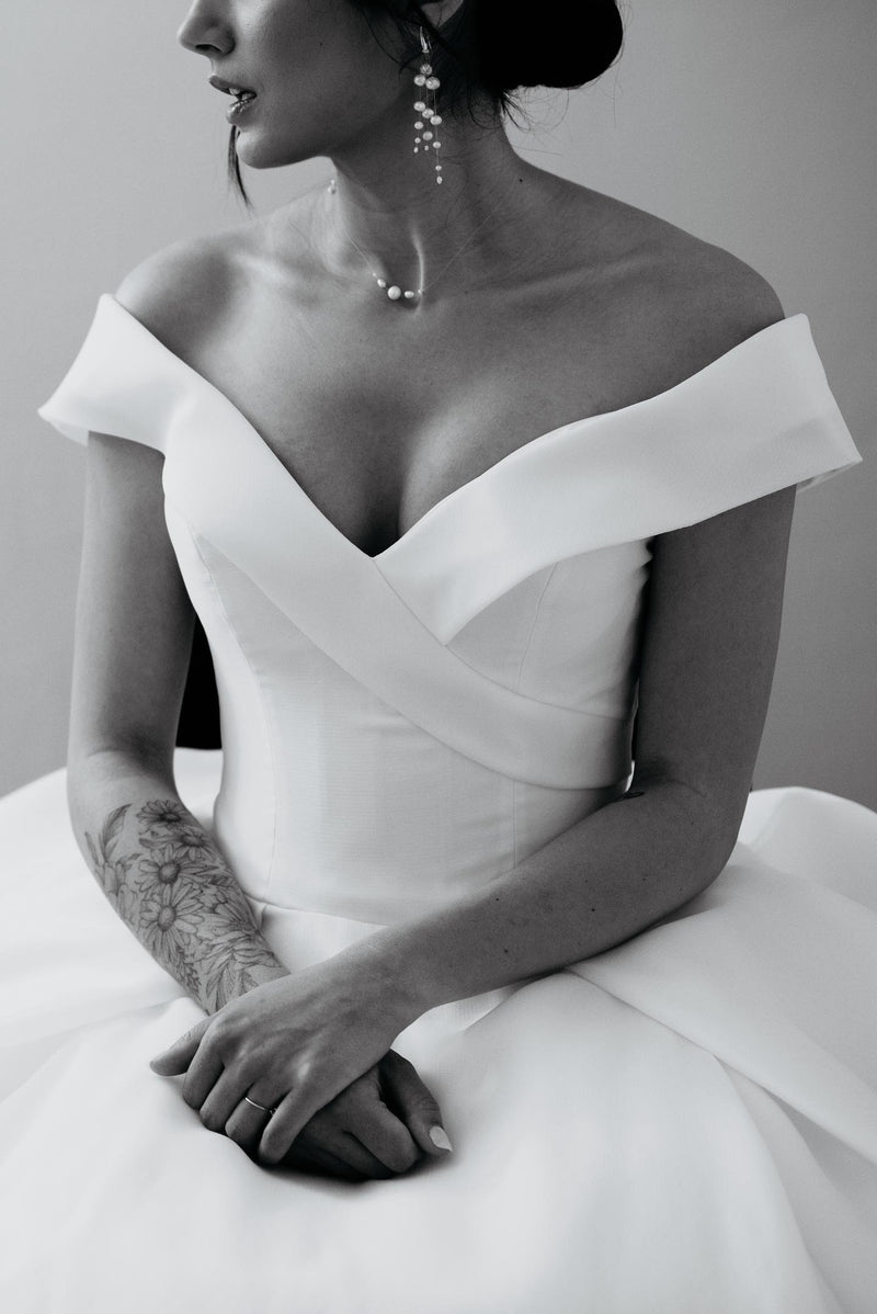 mariée en noir et blanc portant une robe de mariée blanche et des bijoux en perles naturelles
