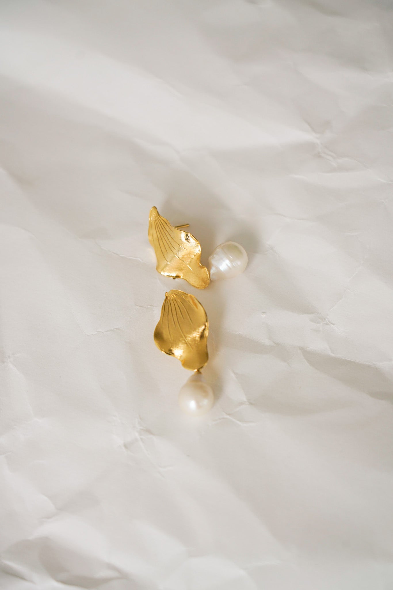 Boucles d’oreilles au design audacieux, composées d’une grande feuille dorée au style asymétrique, large et texturée en haut, s’affinant vers le bas , accompagnée d’une perle dorée imposante à la base. Un bijou sculptural et raffiné, idéal pour une allure moderne et sophistiquée.