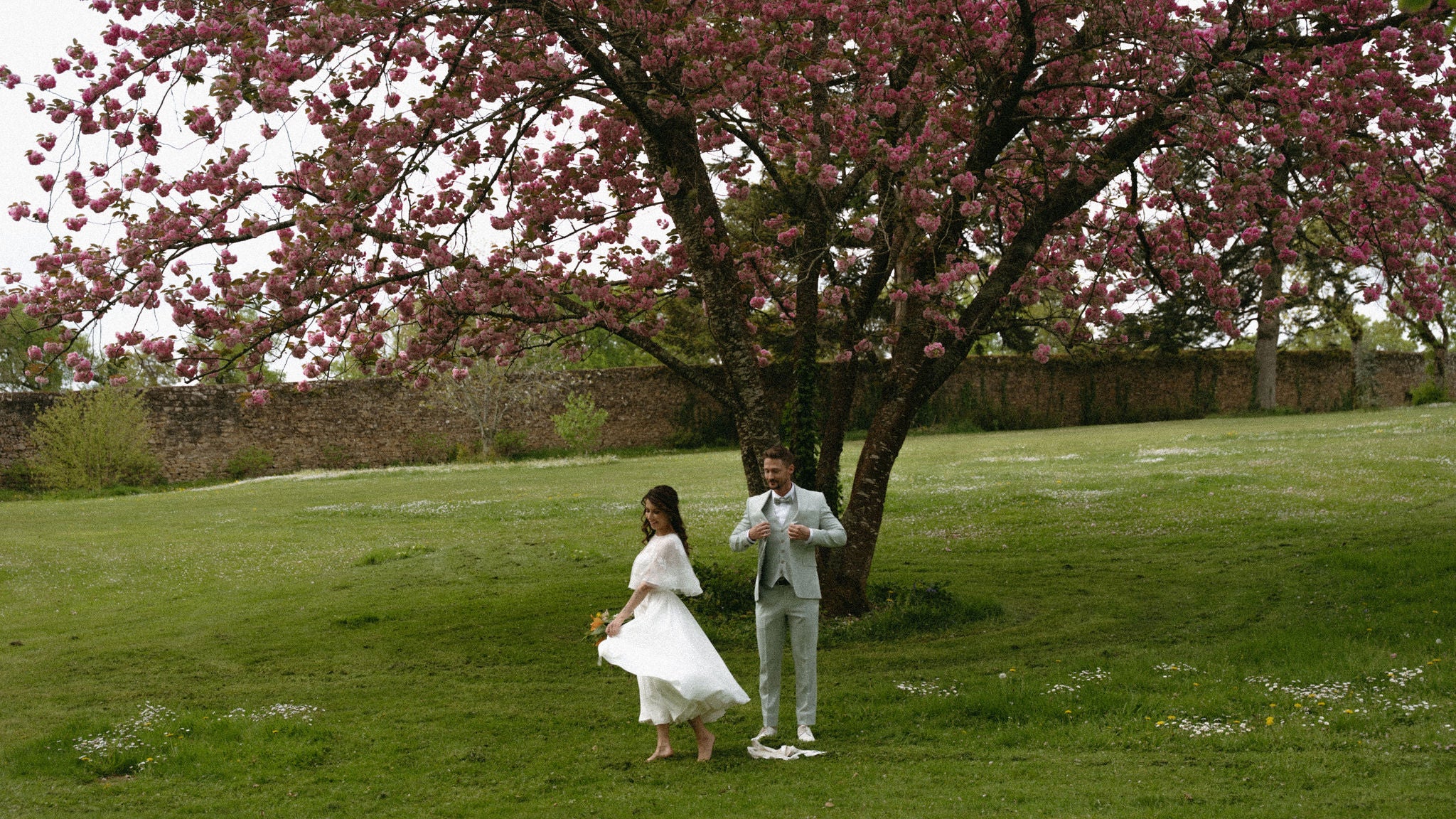 Photo de couple marié, mariage élégant, mariage romantique, couple élégant, tenue de mariée élégante, noces en, château, mariage élégant, inspiration mariage élégant en château, couple joyeux sous un arbre en fleur, mariage estival, mariée pieds nus 