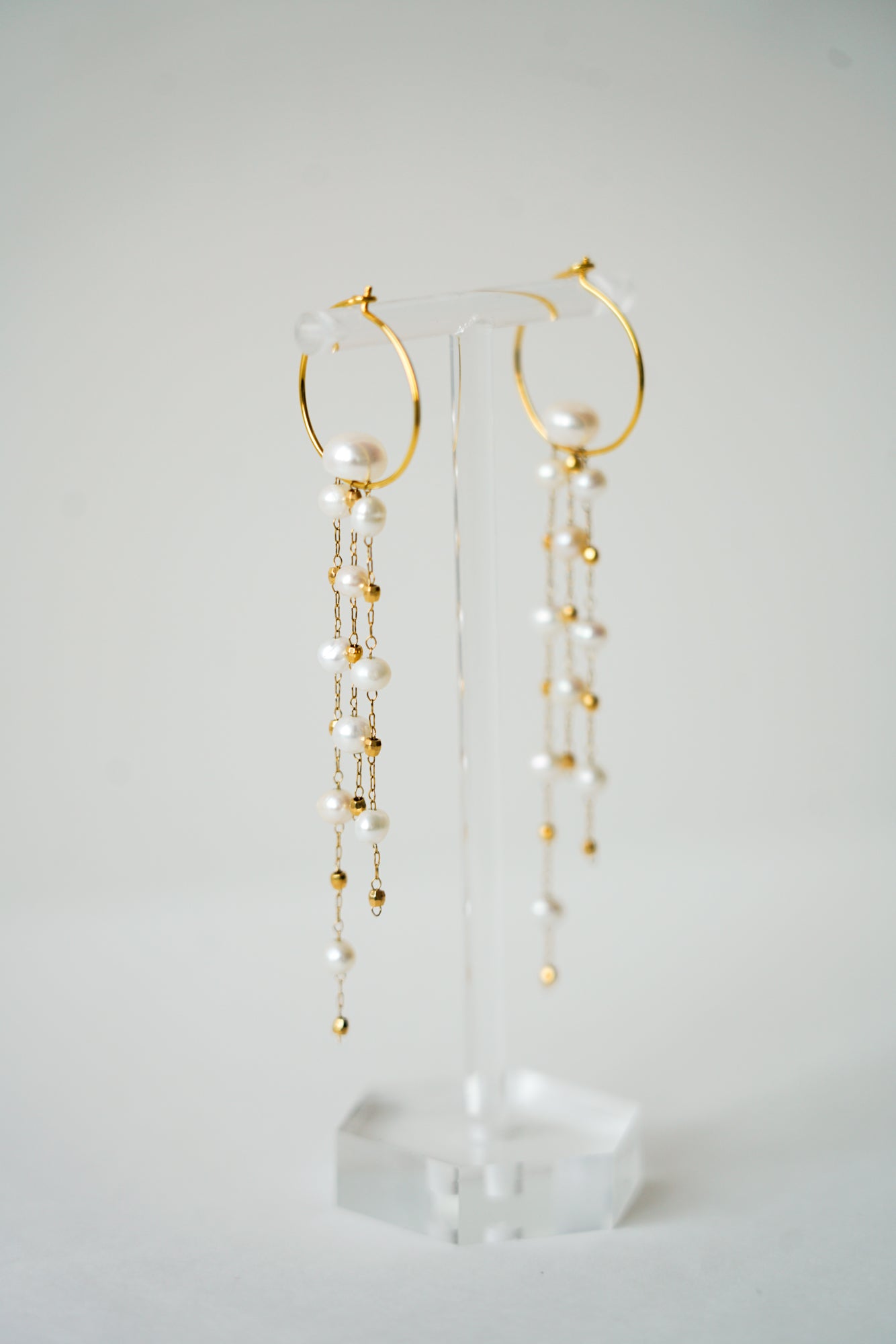 boucles d'oreilles pour une mariée sur un portant à bijou fabriqué en chaine de perles naturelles et un forme arrondi