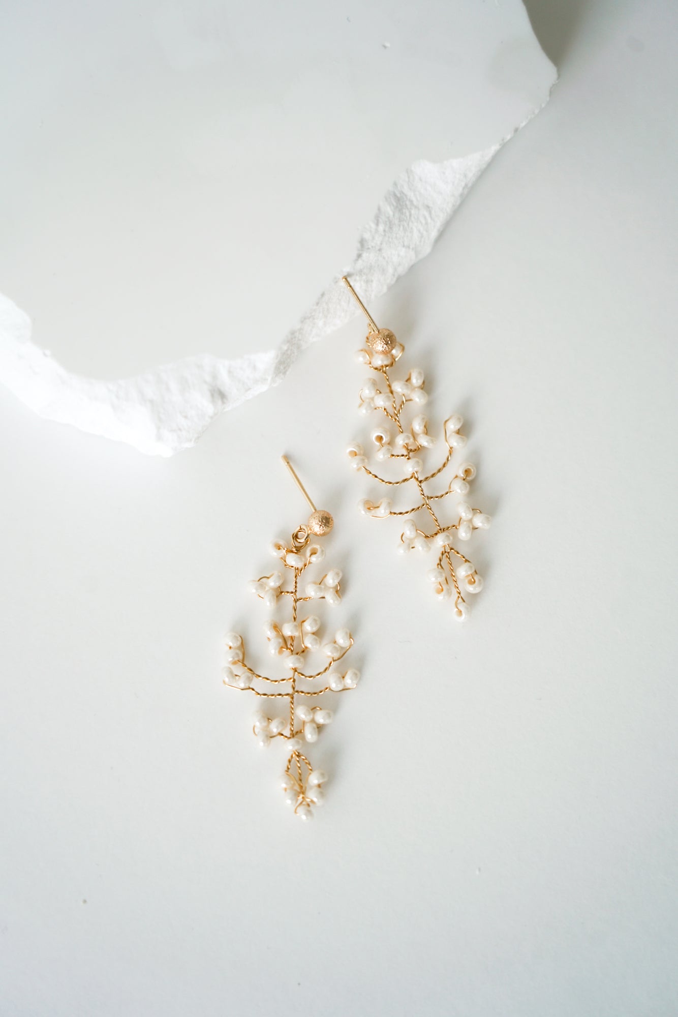 boucles d'oreilles mariée en perles rocailles en forme d'une feuille naturelle avec une pierre blanche