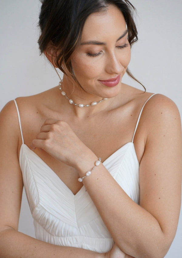 Femme en robe de mariée portant un bracelet et un collier assortis avec des perles naturelles et des cristaux