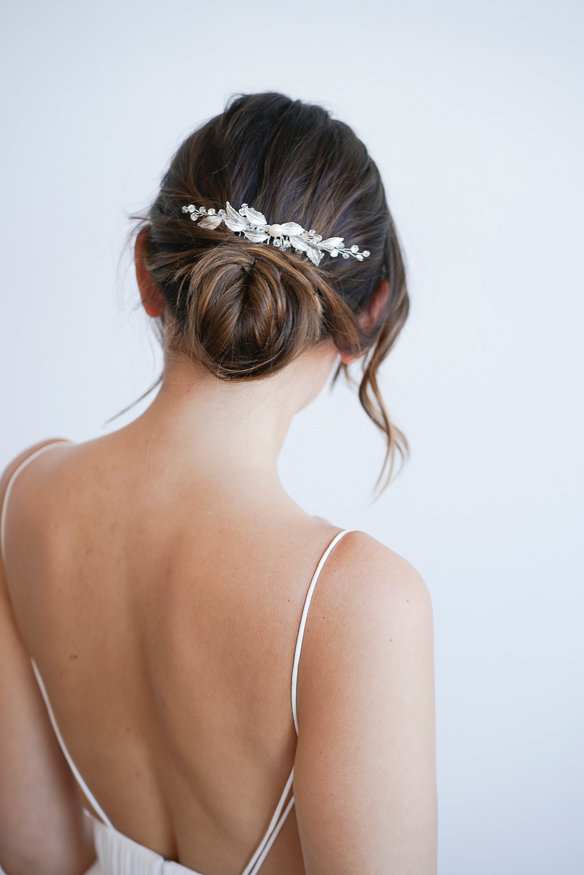 Mariée avec chignon bohème portant un peigne de mariage fait de feuilles en argent, de perles et de cristaux