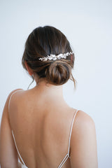Mariée avec un chignon bohème romantique portant un peigne à cheveux fait de feuilles en argent, de perles et de cristaux