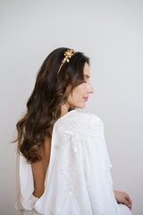 Mariée avec un beau décolleté de dos et des cheveux bouclés au style bohème portant un serre-tête de mariage à fleurs dorées