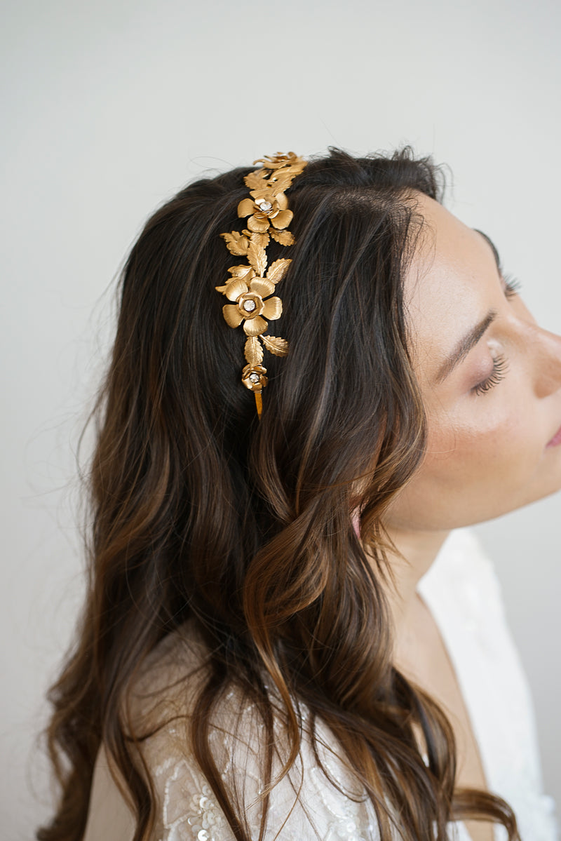 Couronne de mariage doré à fleurs porté par une mariée à la chevelure bouclée