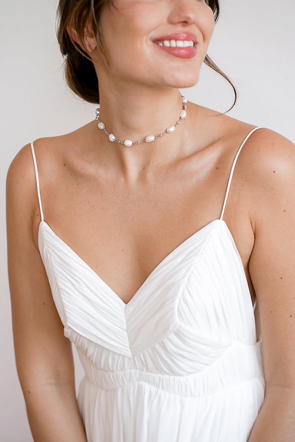 Mariée souriante portant un collier de mariage fait de perles naturelles de culture et de connecteurs argentés