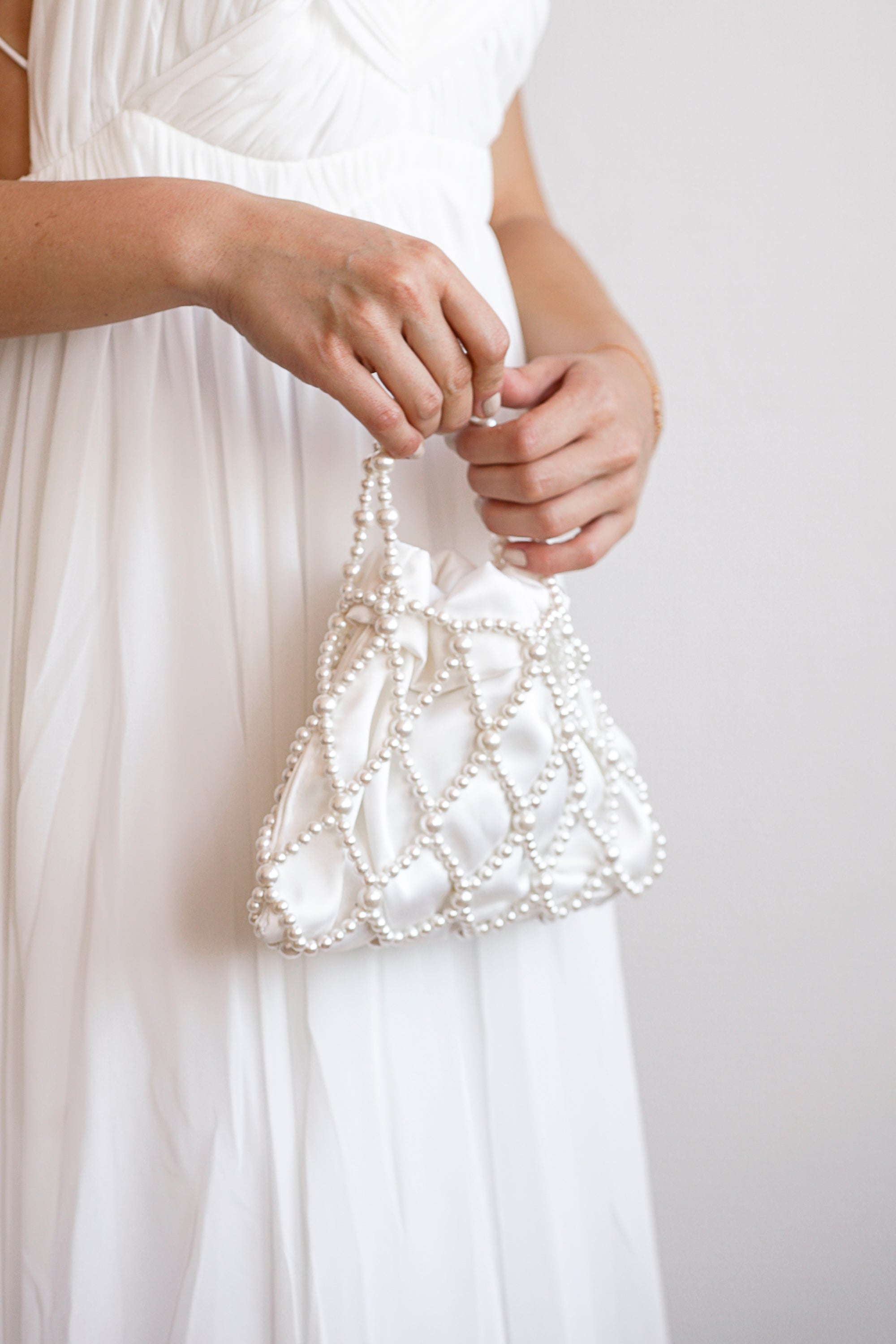 Mariée tenant un sac de mariage malléable en satin et perles blanches