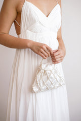 Mariée portant dans sa main un sac de mariée malléable en satin et perles blanches