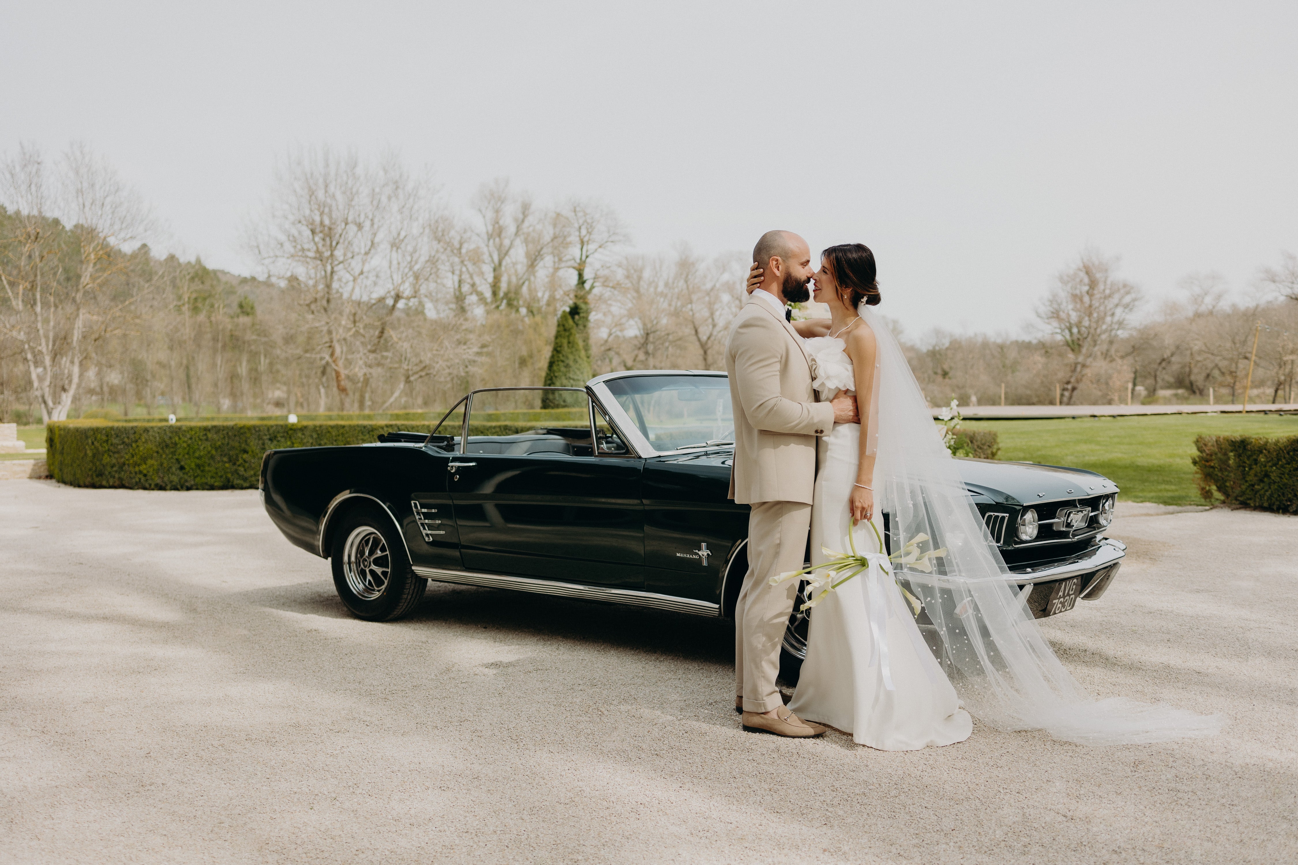 Un couple de jeunes mariés s’enlace tendrement devant une voiture vintage, sous une lumière douce, lors de leur réception de mariage au décor aux nuances matcha et olive, mêlant élégance naturelle et romantisme délicat.
La mariée raffinée en robe blanche tient un bouquet très moderne de fleurs vertes matcha dont une tige devient une anse.