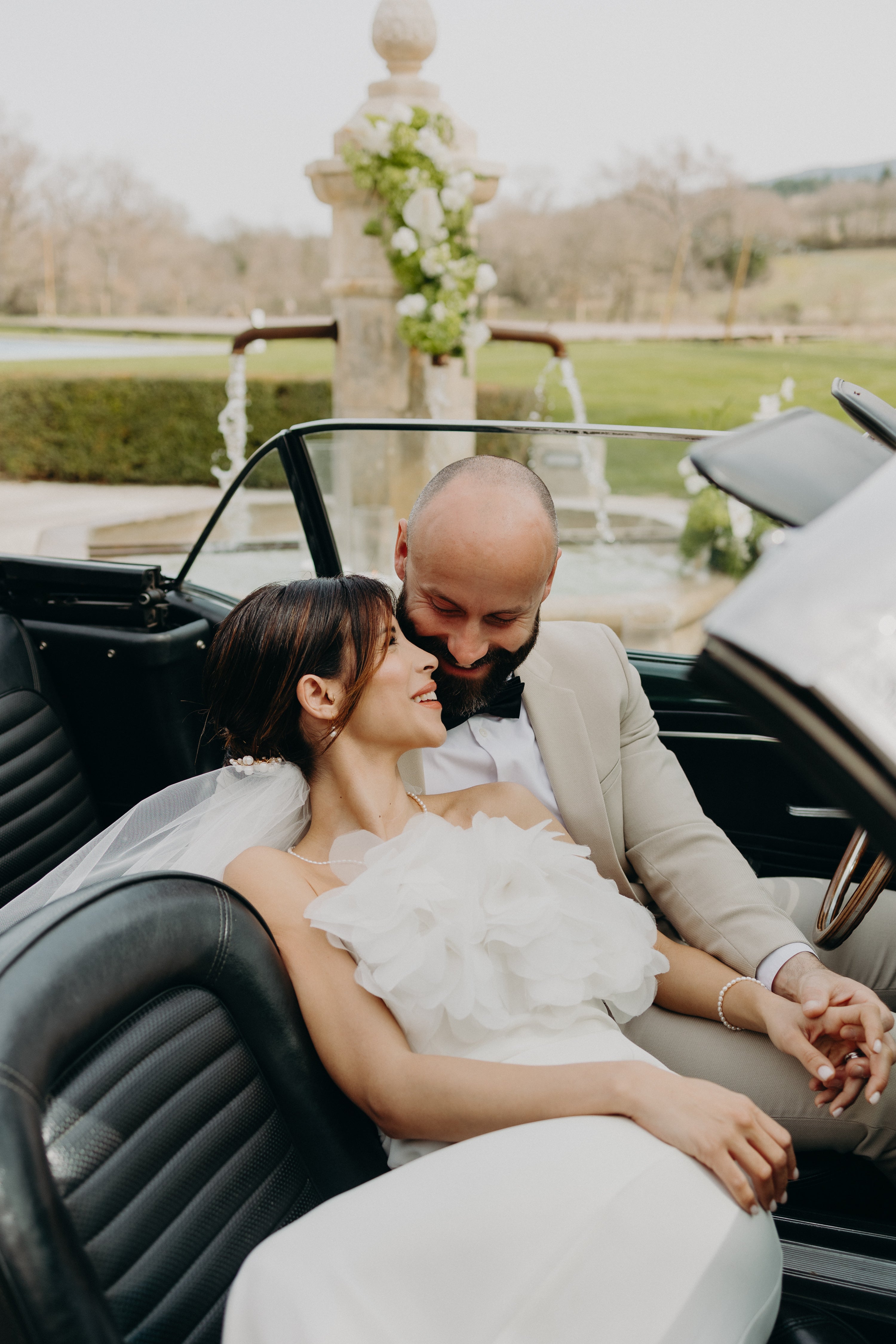 Couple marié élégant enlacés dans une voiture vintage pour leur mariage naturel sur le thème Matcha et Olive. 