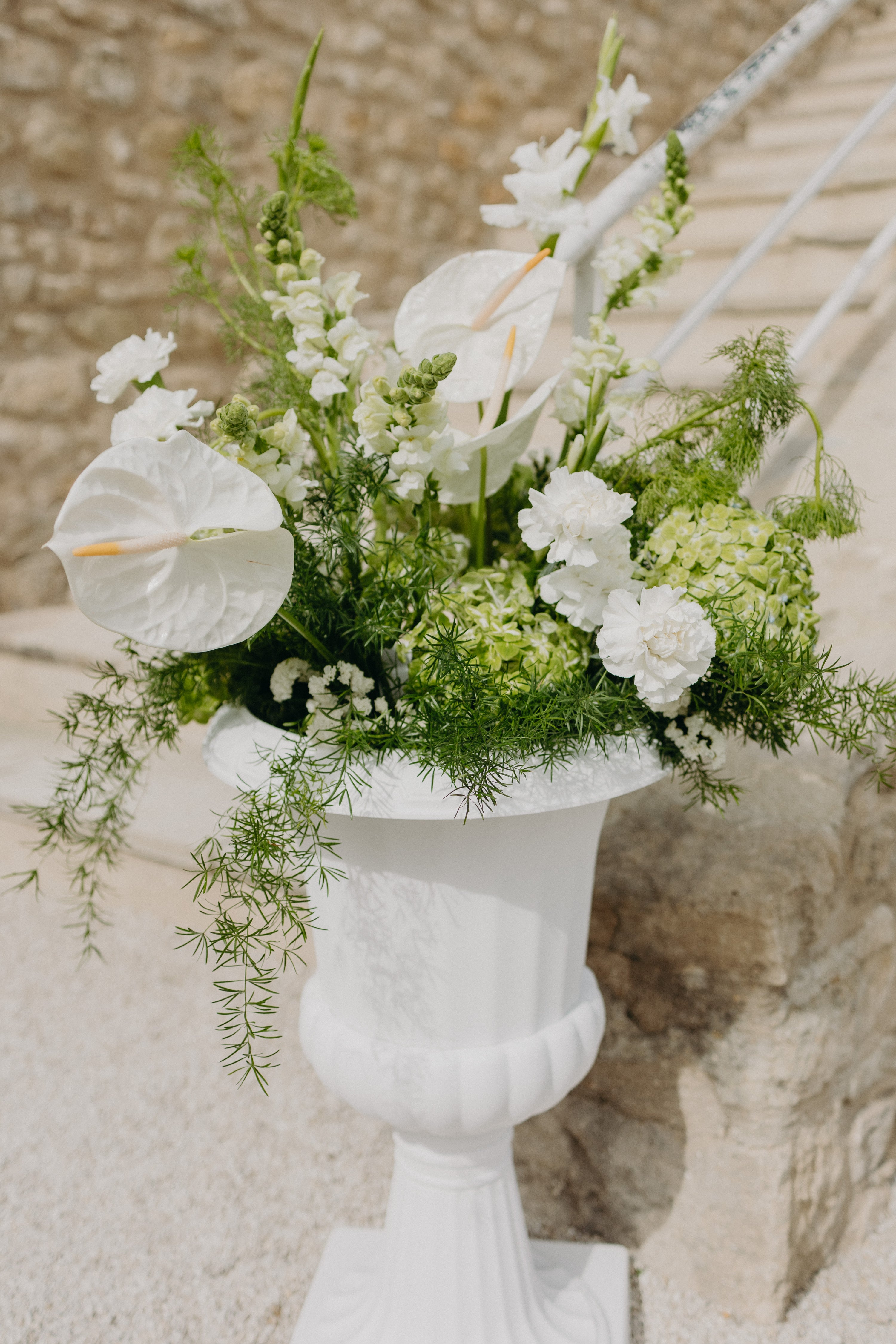Grand vase en marbre élégant contenant des fleurs blanches et de la verdure luxuriante, créant une décoration raffinée et naturelle, parfaite pour une inspiration mariage moderne et naturel aux tons matcha et olive.