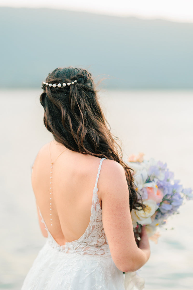 Mariée portant un pic à cheveux minimaliste de mariage en perles naturelles devant le Lac d'Annecy aux tons de couleurs vert d'eau