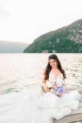 mariée tenant son bouquet de fleurs le jour de son mariage sur le lac d'Annecy avec des boucles d'oreilles en perles naturelles