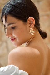 Mariée portant des boucles d'oreilles fleuries en or et perles blanches