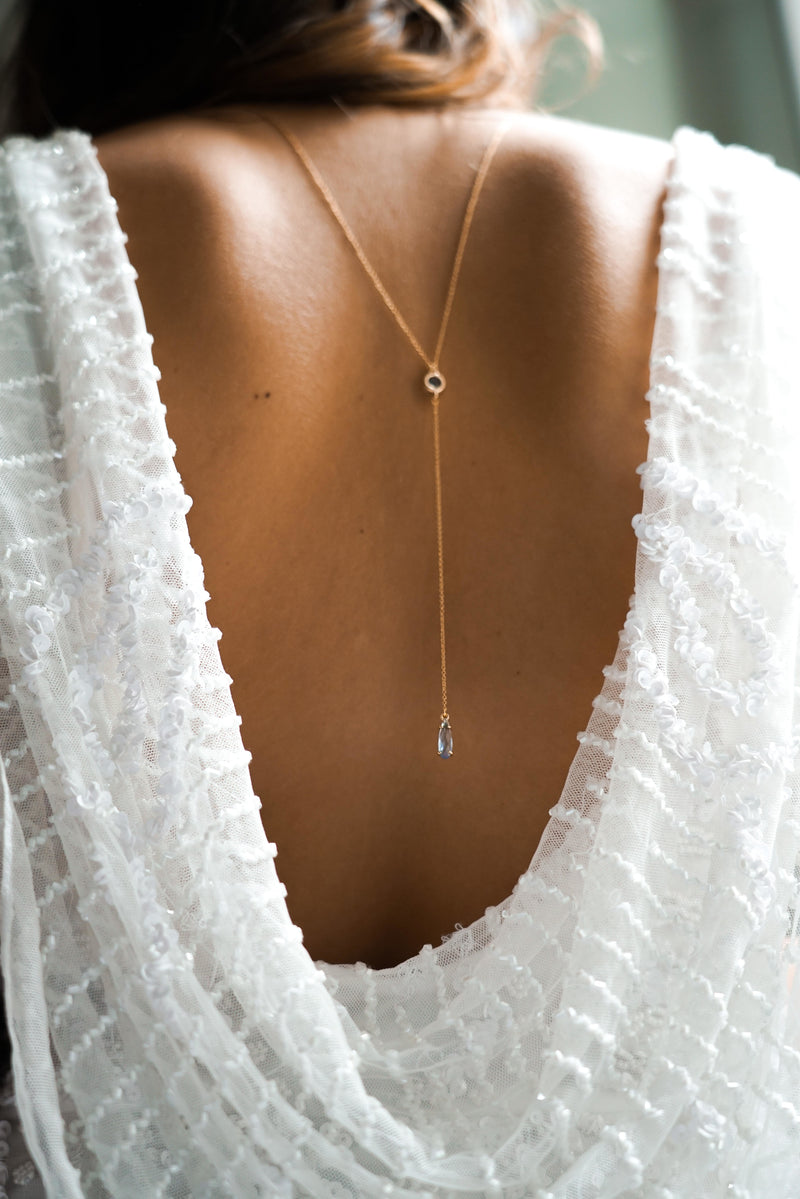collier de dos en goutte de pierre bleu couleur or porté par une mariée
