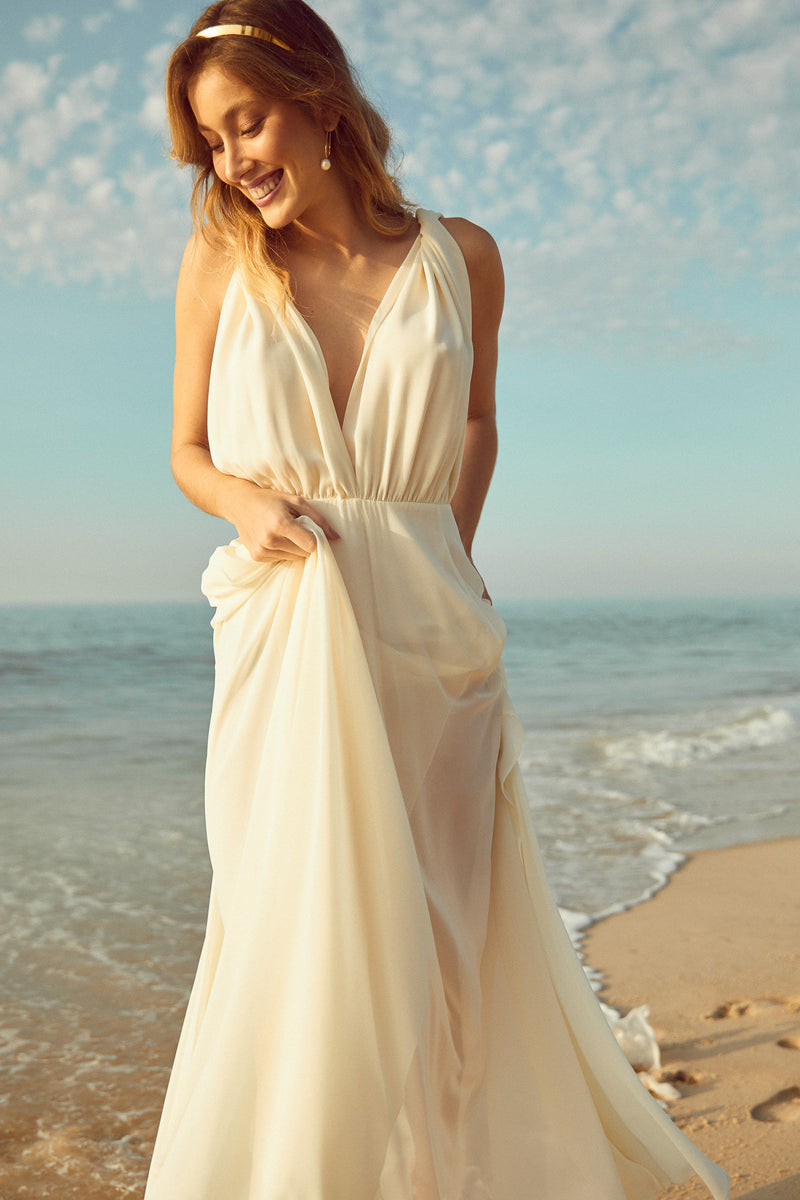 mariée bohème à la plage en robe de mariée blanche portant des boucles d'oreilles fait main