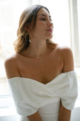 Paire de boucles d'oreilles pendantes dorées à double chaine et deux perles rondes blanches au bout portées par une mariée en robe blanche