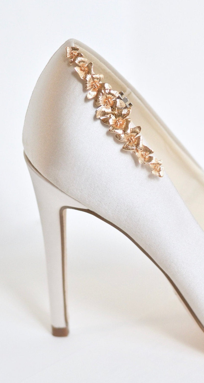 Clip à chaussure à fleurs dorées accroché sur l'arrière de chaussures à talon beige