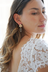 mariée en robe à dentelle blanche portant boucles d'oreilles mariage avec une cristal transparent et une fleur en or