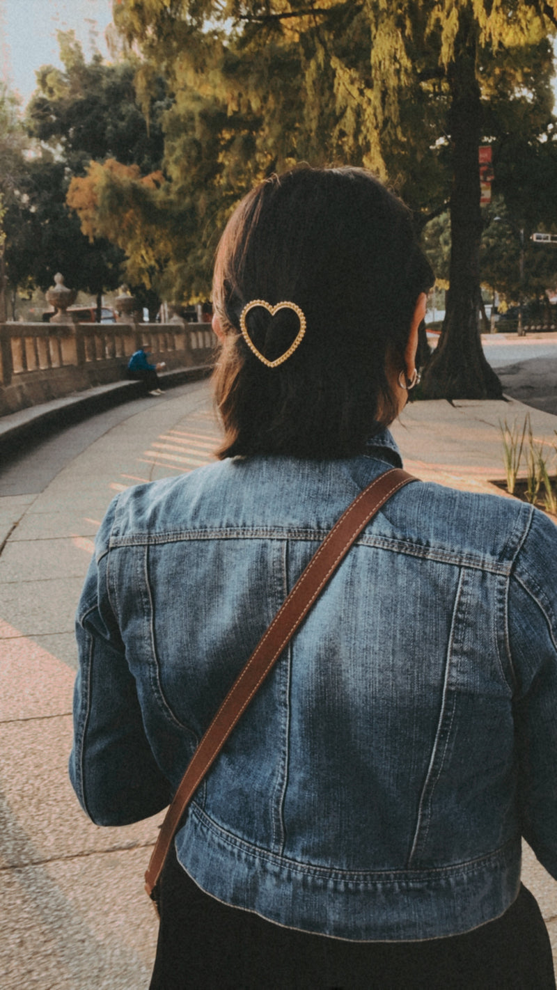 Femme dans un parc avec une barrette en forme de coeur torsadé or
