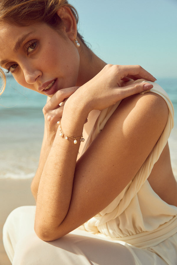 bracelet de mariage avec des perles naturelles blanches et des pierres naturelles bleu porté par une mariée sur la plage