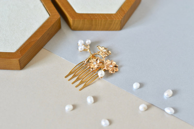 un peigne de chignon pour mariage floral en or avec des perles sur un fond de couleur bleu ciel