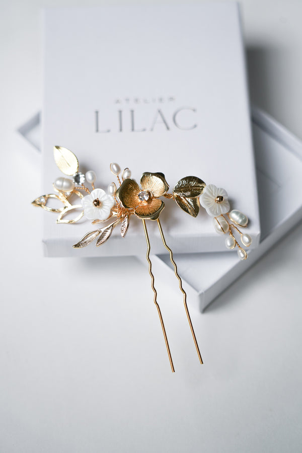 pic de cheveux pour mariage thème floral avec des fleurs en or et en nacre avec des branches de perles naturelles sur un fond blanc