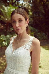 Mariée portant une robe en dentelle avec un collier de mariage bohème à fleurs blanches et or et boucles d'oreilles bohèmes assorties