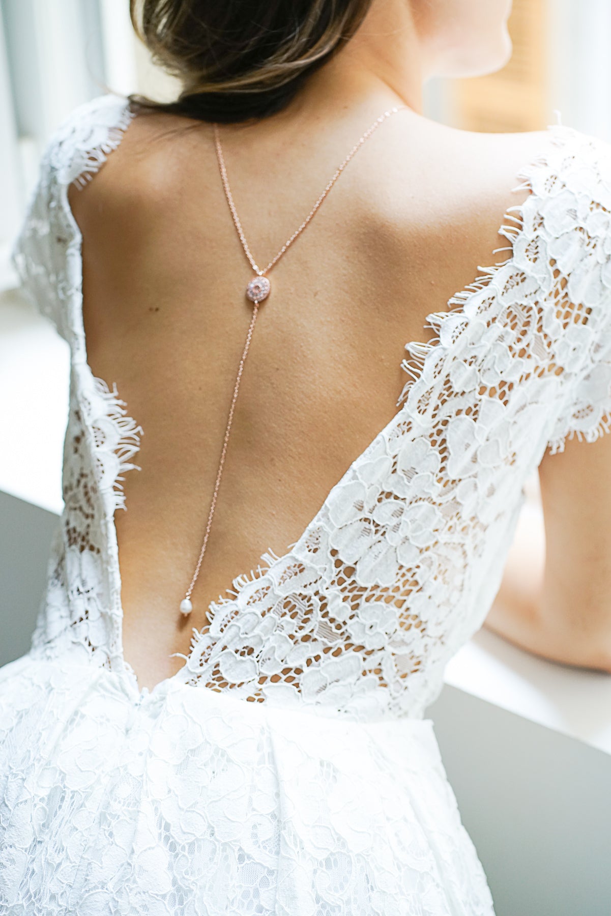 collier de dos porté par une mariée romantique avec une robe en dentelle blanche
