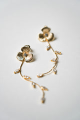 Boucles d'oreilles pendantes fait à la main avec une fleur pour le centre de la boucle et une blanche de feuilles en pendentif prise de près en photo