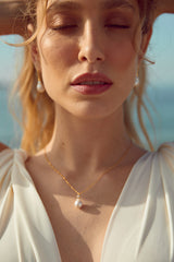 bijoux de mariage collier et boucles d'oreilles en perles naturelles sur une mariée à la plage