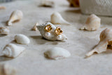 Boucles d'oreilles fleuris or et perles pour un bijoux de mariage romantique sur des coquillages