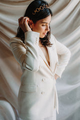 mariée habillée en blanc avec un blazer et portant un headband style bohème vintage à grande maille