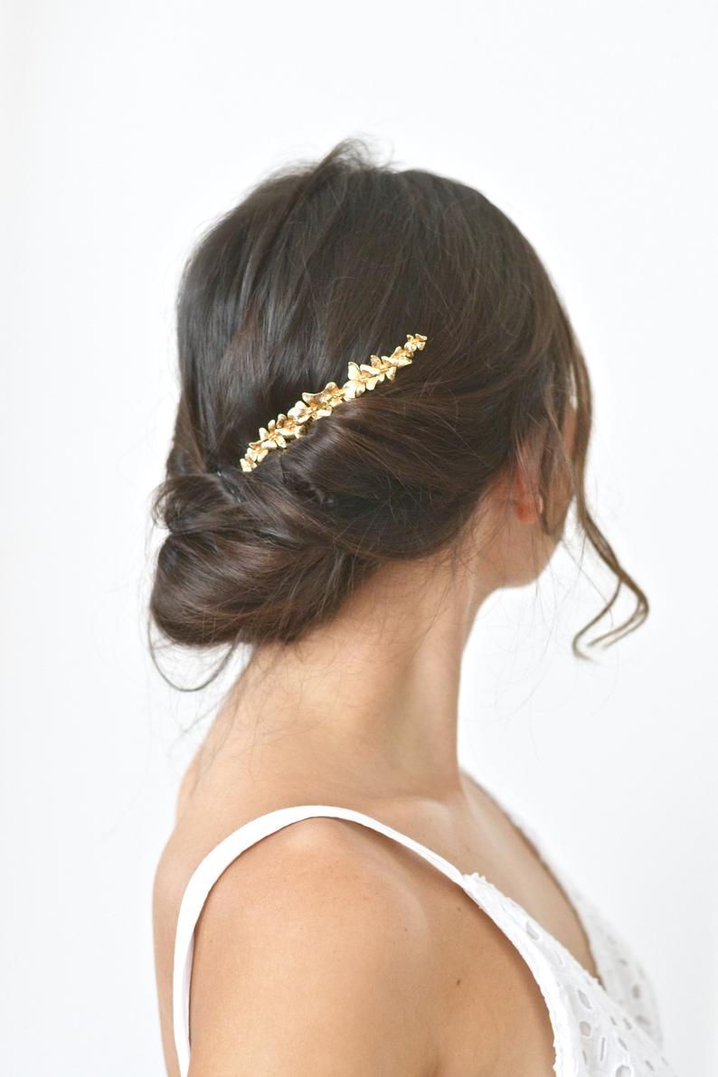 peigne mariage en fleurs en or sur un coiffure en chignon bas cheveux bruns
