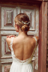 mariée coiffée avec un chignon bas et deux pic de chevaux mariage avec des perles naturelles porté par une femme avec une robe de mariage dos nu