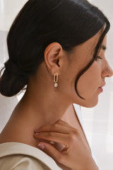 boucles d'oreilles ovale en or avec un cristaux en pendentif porté sur une marée avec un chignon