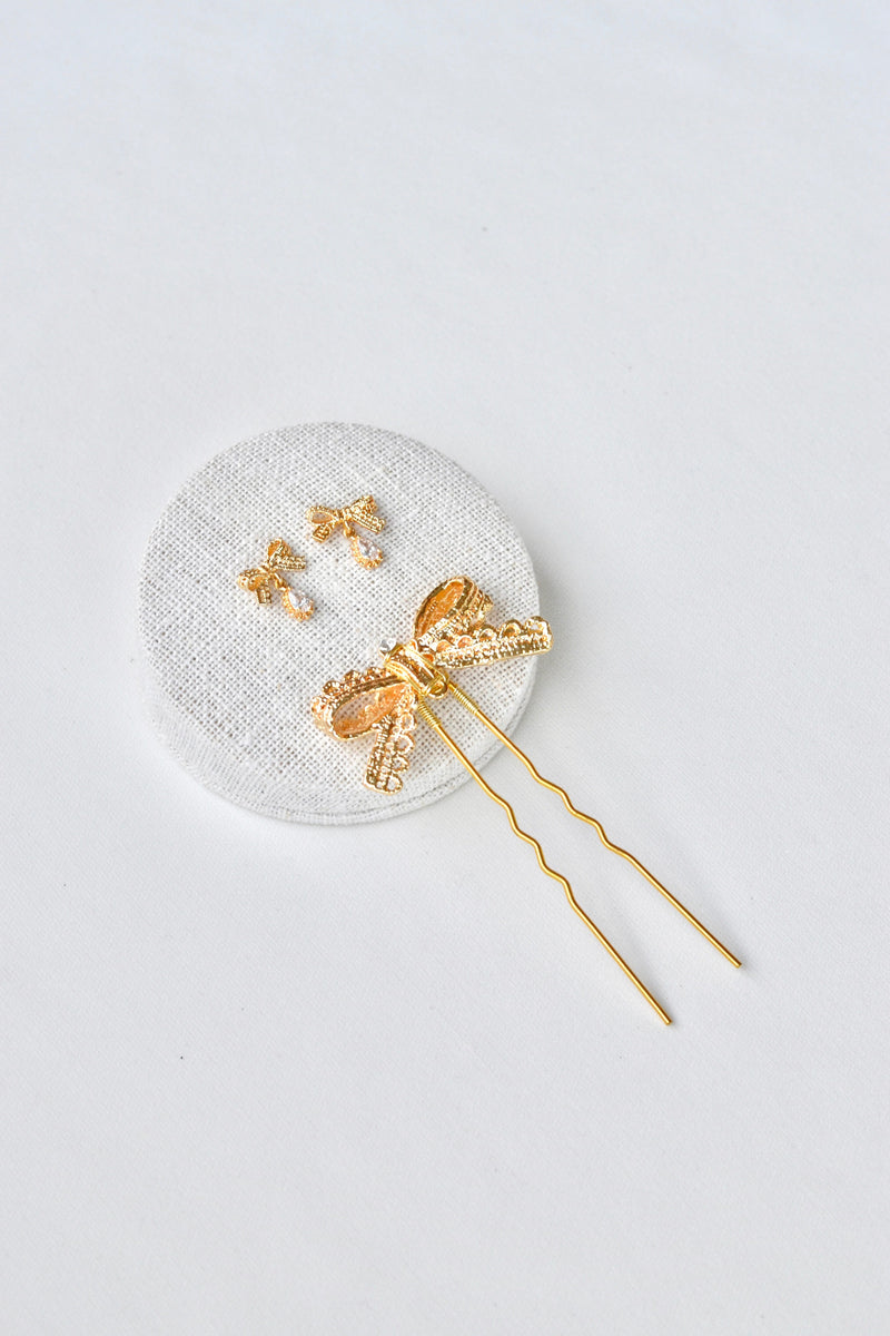 parure d'accessoire de mariage avec un pic de cheveux mariage en or qui forme un noeud en dentelle et les boucles d'oreilles assorties