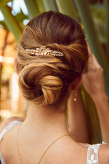 Peigne à cheveux de mariage doré fleuri porté sur un chignon de mariage bohème