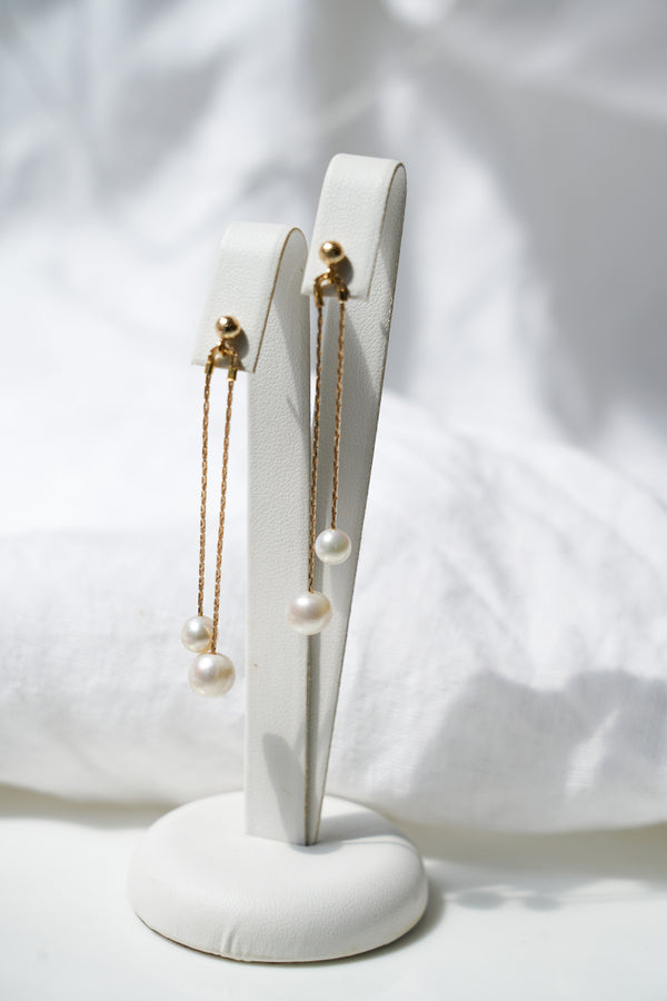Paire de boucles d'oreilles pendantes dorées à double chaine et deux perles rondes blanches au bout
