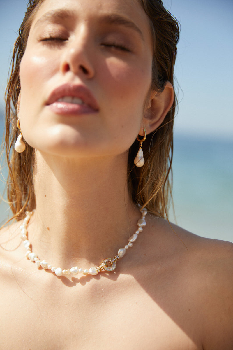 boucles d'oreilles baroques pour mariage en perles naturelles porté par une mariée sur la plaage