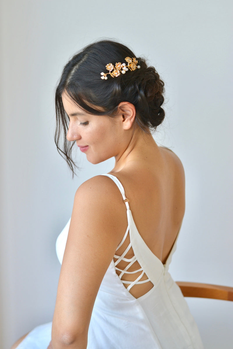 mariée portant un peigne de chignon pour mariage floral en or avec des perles et une robe blanche