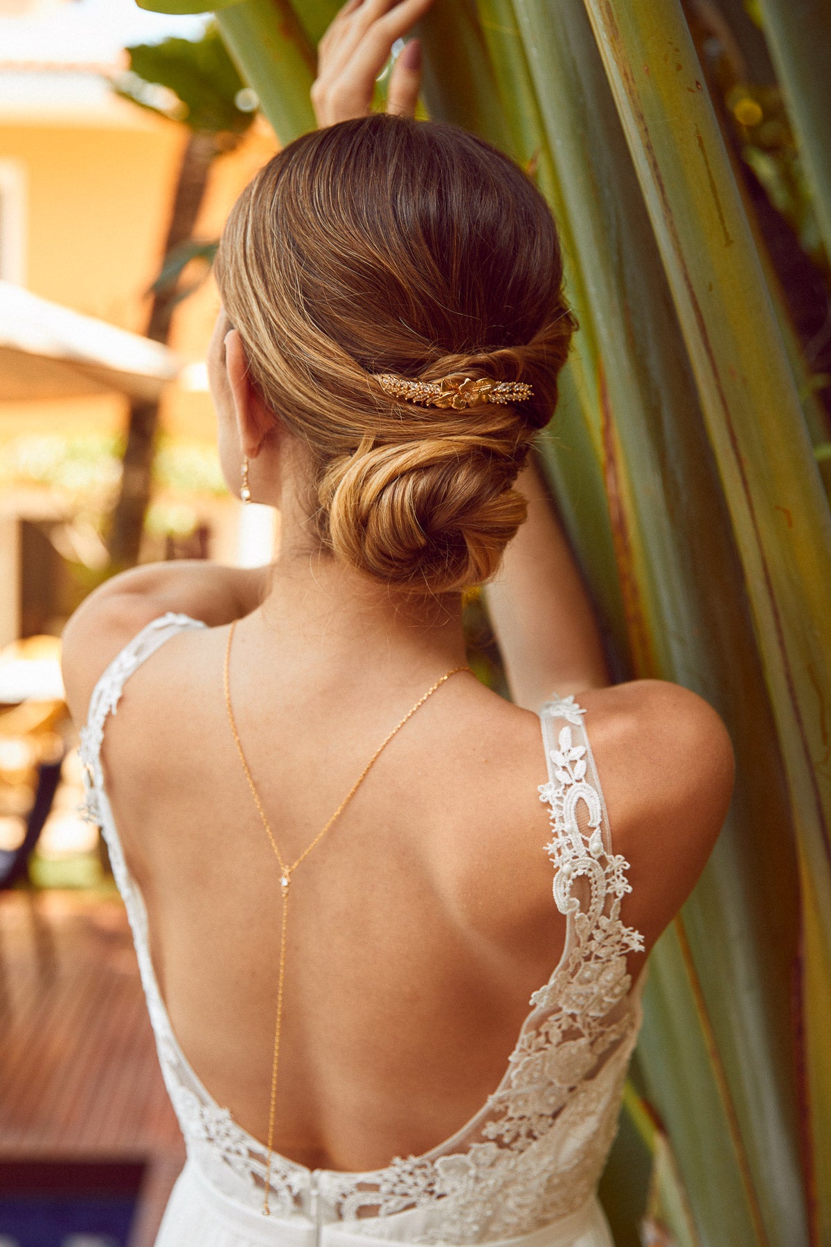 Mariée portant un peigne de mariage floral et bohème doré et un collier de dos assorti