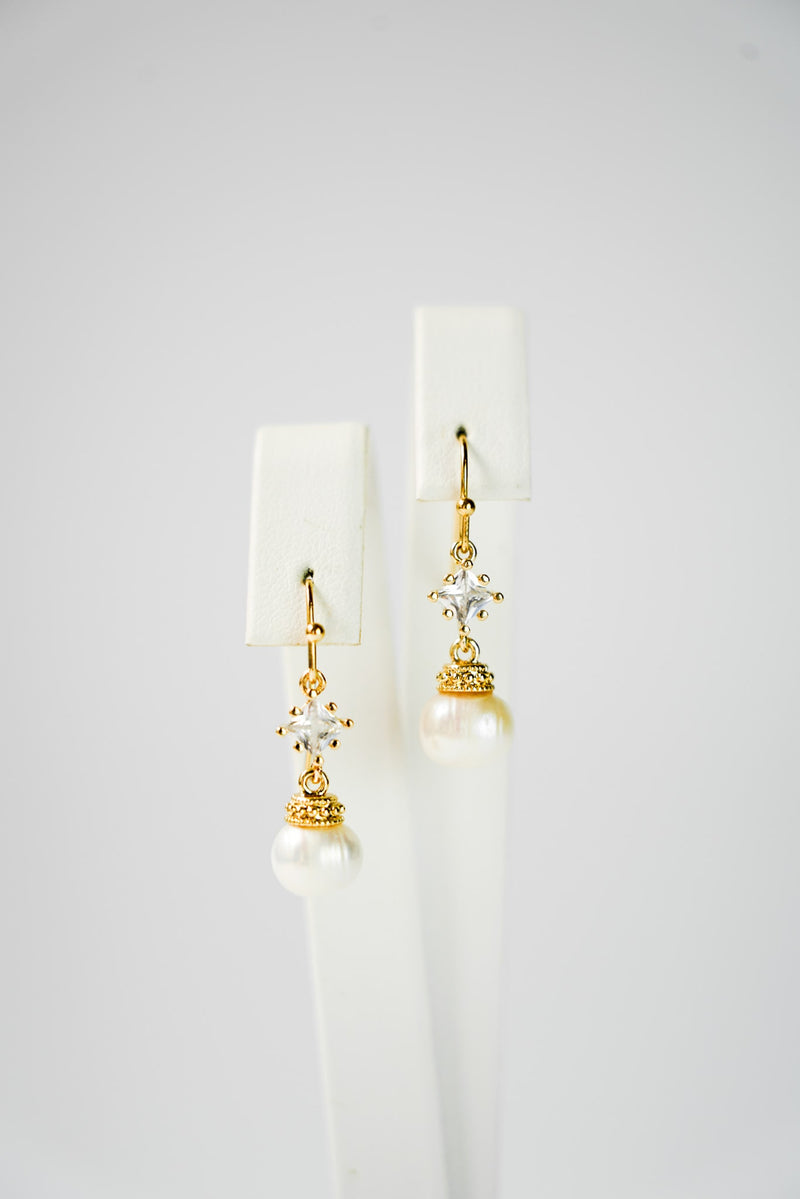 boucles d'oreilles pour mariage avec un cristaux et une perle en pendentif sur un socle de bijou