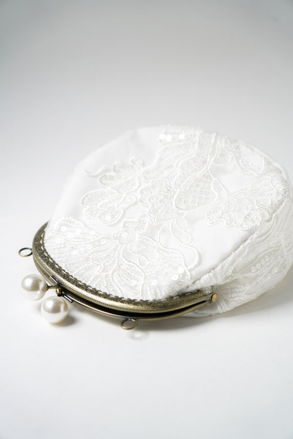 sac de mariage blanc cousu avec un tissu en dentelle fleuri et une attache bronze avec deux perles