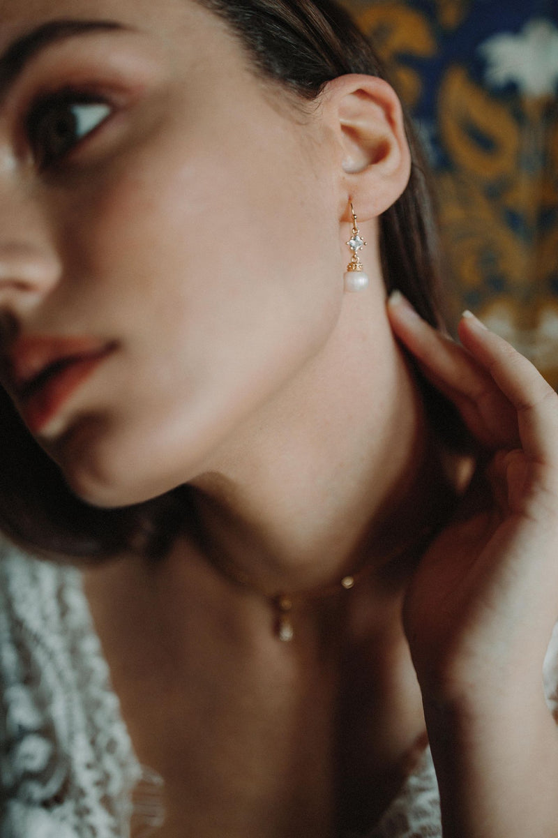 mariée portant des boucles d'oreilles pédante avec un cristaux et une perle  