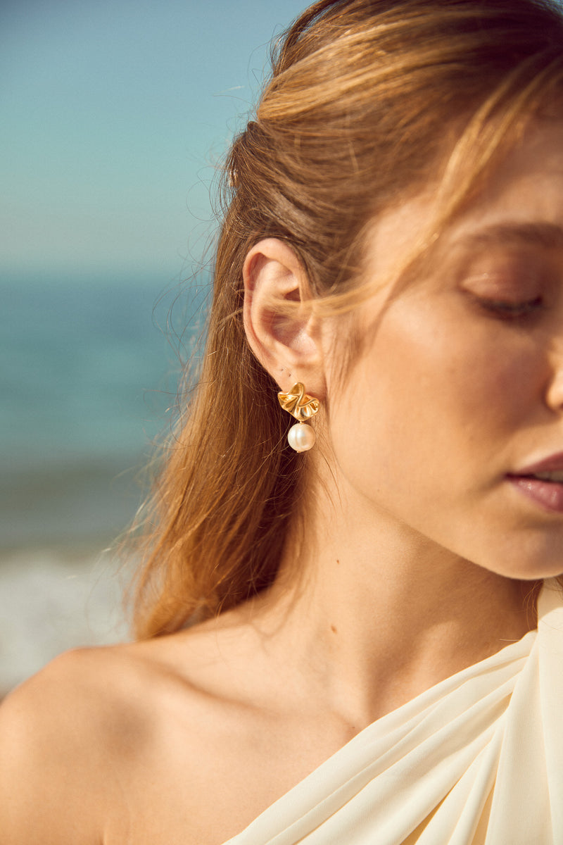 Mariée portant des boucles d'oreilles en or minimaliste avec perle blanche