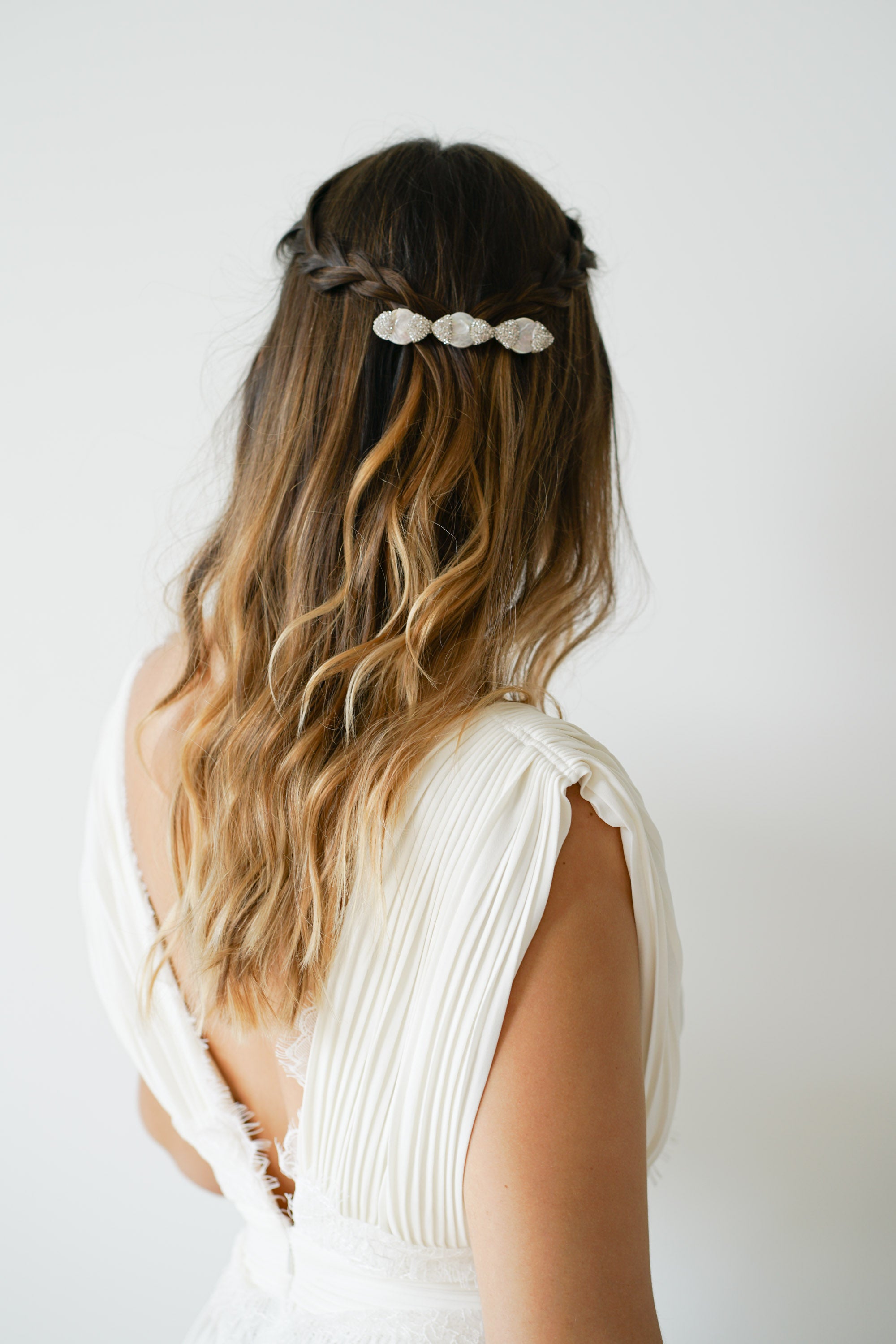 coiffure de mariée en demi-queue avec une barrette blanche